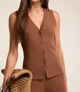 Blusa estilo chaleco color marrón, confeccionada en ribana, con abotonado delantero, sin mangas y con textura acanalada.