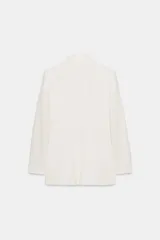 Blazer cruzada de color negro, confeccionada en tejido con lino. Presenta cuello solapa con muescas, hombreras, manga larga, falsos bolsillos con solapa y cierre frontal cruzado con botones metálicos dorados.