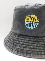 Gorro tipo bucket de denim gris oscuro con bordado frontal de la marca Rusty en amarillo y celeste.