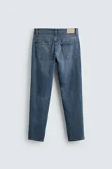 Pantalón de jean negro, corte slim fit, con tiro medio, cinco bolsillos, efecto lavado y cierre frontal con cremallera y botón.