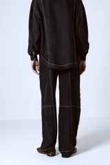 Pantalón negro de corte recto con costuras blancas a contraste.