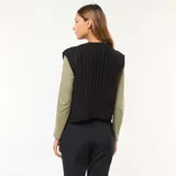 Chaleco de punto grueso color negro, sin mangas, con cuello redondo y cierre frontal con botones dorados.