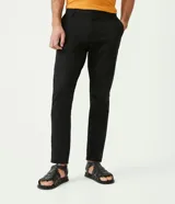 Pantalón de vestir color marrón, de corte slim y largo cropped. Confeccionado en tejido de algodón liso, con bolsillos laterales y traseros. Cierre frontal con botón y cremallera.