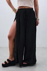 Pantalón palazzo negro con cintura elástica y aberturas laterales altas.