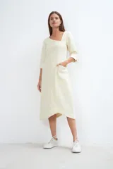 Vestido midi color crema con escote cuadrado, manga francesa con tajo y bolsillo lateral. Confeccionado en lana fina sin teñir.