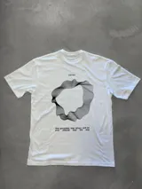 Remera blanca de corte oversize con estampado gráfico abstracto en negro en la espalda, que incluye la palabra "OSTEN" y la frase "stay grounded, stay driven, and let your attitude lead the way".