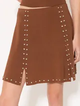 Pollera marrón tejida con calce al cuerpo, de largo arriba de las rodillas y detalle de tachas plateadas.