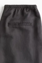 Pantalón recto gris oscuro de tejido vaporoso en mezcla de lino. Modelo holgado con elástico y cordón de ajuste en la cintura, bolsillos laterales y traseros insertados.