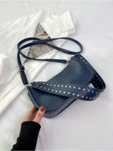 Bolso bandolera negro de cuero sintético con tachas plateadas en las correas.