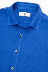 Camisa azul de lino con botones de coco y corte recto.