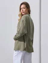 Camisa blanca de algodón con textura arrugada, cuello con solapa, abertura central con botones y bolsillo aplicado en el pecho. Mangas largas con largo regulable mediante presilla y botón.