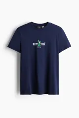 Remera azul marino de algodón con cuello redondo y estampado frontal con un gato disfrazado de Estatua de la Libertad y la frase "Me-OW-York City".