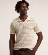 Remera polo de manga corta color crema, con cuello en V y textura patchwork.