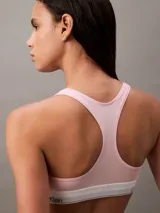 Conjunto Calvin Klein color rosa pálido, compuesto por un corpiño deportivo sin relleno y una tanga, ambos con banda elástica blanca con el logo de la marca.