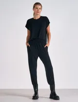 Enterito negro de modal y poliéster, con mangas cortas, escote redondo, laterales abiertos, cintura elastizada y bolsillos laterales. El pantalón es estilo jogger con terminación ajustada en el ruedo.