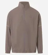 Campera deportiva color marrón, con cuello alto, cierre frontal con cremallera, manga larga, bolsillos laterales y detalles de etiqueta aplicada y rayas.