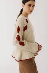Sweater color gris claro con cuello redondo, mangas largas acampanadas y aberturas circulares en hombros y mangas con detalles de tela blanca.