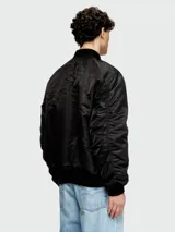 Campera bomber negra de hombre, estilo aviador, con cuello y puños acanalados. Presenta cierres metálicos visibles y bolsillos frontales con solapa y broche.