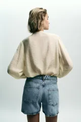 Shorts de jean celeste con tiro alto, cinco bolsillos y cierre frontal cruzado con cremallera y botones.