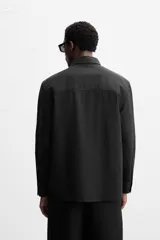 Camisa color crema de corte relaxed fit, confeccionada en tejido de mezcla de algodón suave al tacto. Tiene cuello solapa, manga larga con puños abotonados, un bolsillo de parche en el pecho y cierre frontal con botones.