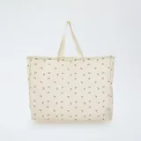 Bolso tipo tote bag grande de tela color beige con estampado de cerezas rojas y hojas verdes.