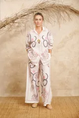 Conjunto de camisa de manga larga con cuello y pantalón palazzo, ambos con estampado de flores y hojas en tonos rosa, gris y marrón sobre fondo blanco.