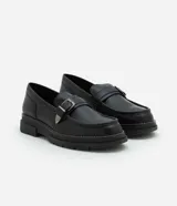 Zapato negro de cuero sintético con punta redonda, detalle de hebilla plateada y suela track.