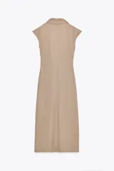 Vestido midi color beige con cuello polo, escote en pico, manga sisa caída y detalle de drapeado lateral. Cierre frontal con botones metálicos en relieve.