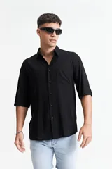 Camisa negra oversize de manga corta con cuello clásico y bolsillo en el pecho.