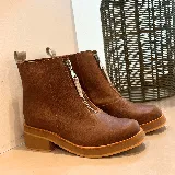 Botas cortas de cuero color marrón con cierre frontal con cremallera, suela de goma y taco bajo.