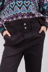 Pantalón negro de tiro alto con elástico interno en la cintura, botones falsos y terminación con volado. Tiene bolsillos aplicados en delantero y falsos en espalda.