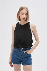 Blusa blanca de algodón sin mangas, con cuello a la base, abertura en la espalda y lazo ajustable.