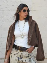 Campera bomber oversize color chocolate, con cierre frontal y detalles de ojales metálicos en la solapa. Confeccionada en gamuza, tiene mangas abullonadas con puños elásticos.