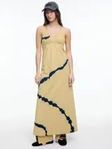Vestido largo de algodón color beige con estampado tie-dye azul. Tiene breteles finos, escote en V y espalda descubierta.