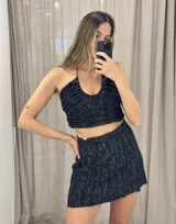 Minifalda negra tejida con hilo lurex plateado, corte acampanado y pretina elástica.
