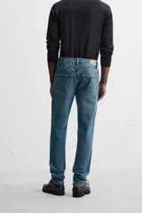 Pantalón de jean azul oscuro, corte slim fit, tiro medio, cinco bolsillos, tejido elástico y efecto lavado.