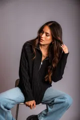 Buzo de punto color rosado, con cuello polo y cierre frontal parcial, de manga larga y diseño holgado.