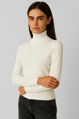 Polera de tejido de punto color blanco hueso, con cuello tortuga acanalado y puños y ruedo con terminación acanalada.