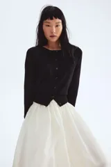 Saco negro de punto fino y suave de mezcla de viscosa con botones adelante. Cuello, puños y bajo en punto elástico acanalado.