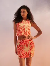 Minifalda color beige con estampado de hojas rojas y abertura lateral.