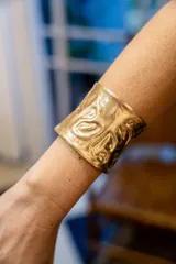 Brazalete ancho color dorado con textura irregular.