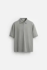 Polo gris de punto con cuello solapa y cierre frontal de cremallera. Corte regular fit, manga corta y acabados en rib.
