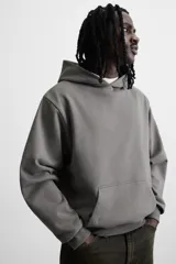 Sudadera con capucha gris confeccionada en tejido de algodón con interior de rizo, manga larga, bolsillo tipo canguro y terminaciones en rib.