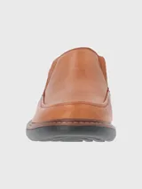 Zapato de vestir color marrón, sin cordones, de cuero vacuno liso. Tiene elásticos laterales, plantilla de cuero y algodón orgánico, y suela de goma EVA.