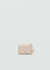 Monedero pequeño color beige con efecto piel y detalle de abalorios. Tiene cierre de solapa con botón magnético, bolsillo interior y bolsillo lateral con cierre de cremallera.