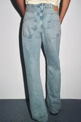 Pantalón de jean celeste de corte recto y tiro medio, con cinco bolsillos y cierre frontal con cremallera y botón metálico.