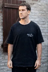 Remera negra de algodón con estampa en la espalda de un cartón de jugo con carita sonriente sobre un fondo a cuadros y la frase "Good Vibes Juice".