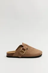 Zuecos negros con base de corcho, puntera cerrada y hebilla dorada decorativa.