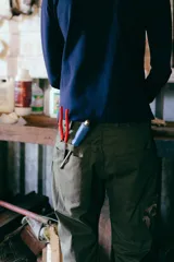 Pantalón de trabajo verde oliva, de tiro medio, confeccionado en gabardina de algodón. Presenta cinta utilitaria trasera, cintura ajustable, bolsillo para metro bordado y cinta reflectiva en los bajos.