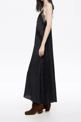 Vestido largo de corte línea A, confeccionado en tejido plisado con estampado de piel de serpiente en tonos marrón, negro y celeste. Presenta escote en pico pronunciado con tirantes de lazo ajustables y detalles de encaje negro en el escote y a lo largo del frente y laterales.